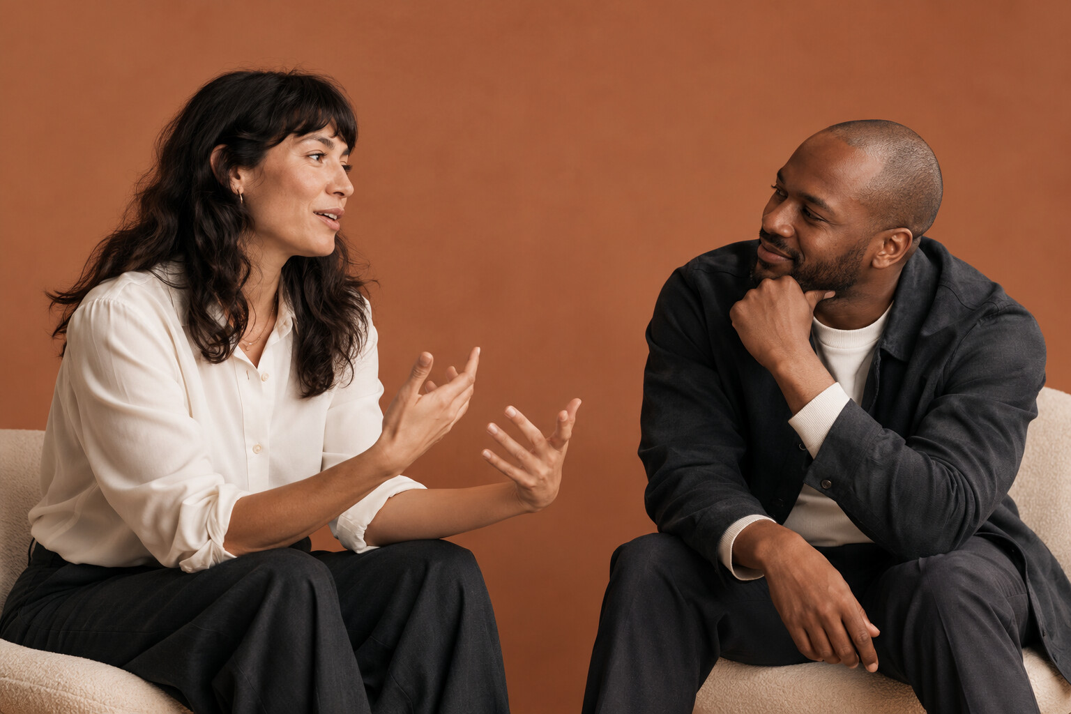 Illustrative studio photograph of a supportive conversation against a clay backdrop
