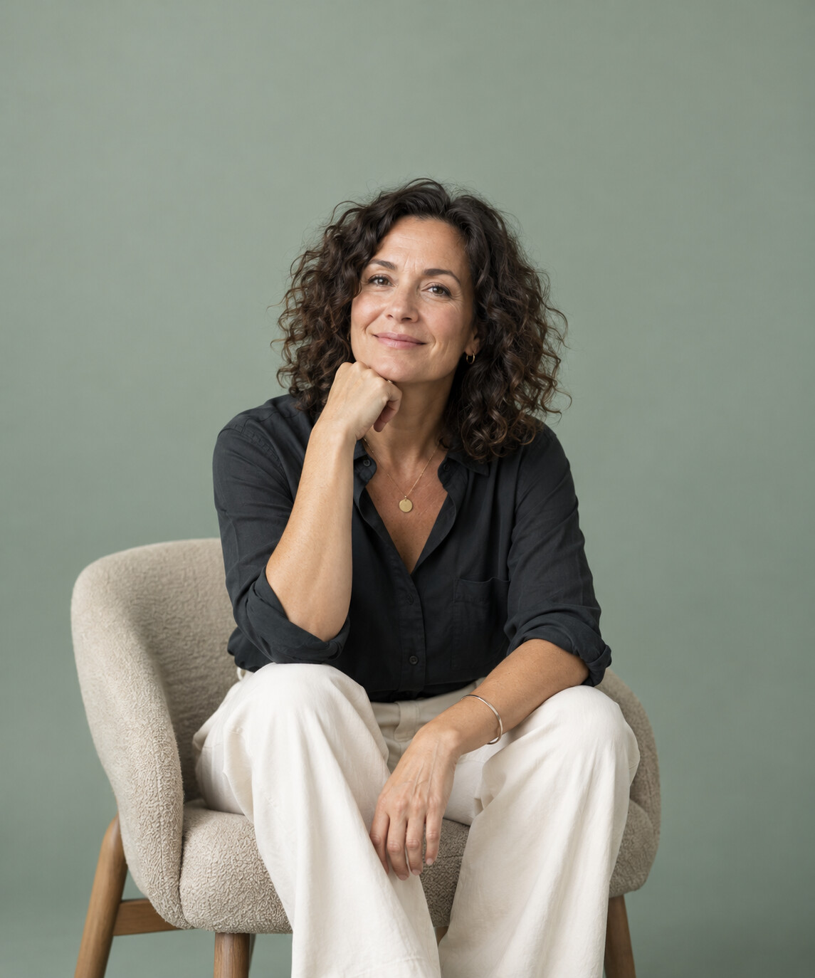 Illustrative studio photograph of an approachable professional against a sage backdrop