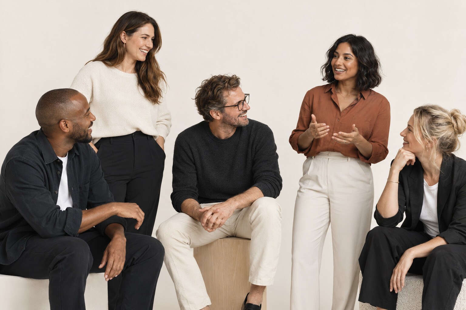 Illustrative studio photograph of colleagues in conversation against a cream backdrop
